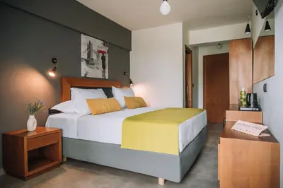 a bedroom with a large bed and a table at Amphitryon City Hotel in Rhodes Town
