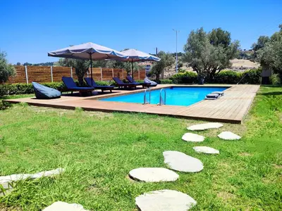 a backyard with a swimming pool with chairs and an umbrella at Villa Photerra, A Luxury familly Villa with pool in Koskinou