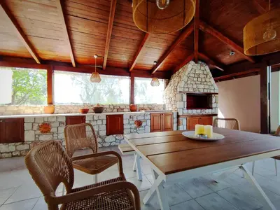 a dining room with a wooden table and chairs at Villa Photerra, A Luxury familly Villa with pool in Koskinou