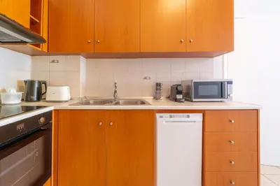 a kitchen with wooden cabinets and a sink and a microwave at Residence City Luna in Rhodes Town
