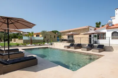 a swimming pool with lounge chairs and an umbrella at Anthi Luxury Residence in Triánta