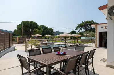 a wooden table and chairs on a patio with a pool at Anthi Luxury Residence in Triánta