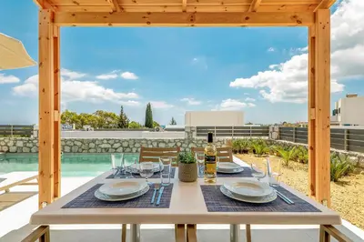a table with plates and wine glasses on a patio at Gennadi GEMS Villas in Gennadi