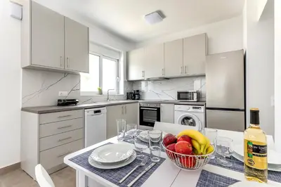 a white kitchen with a table with a bowl of fruit at Gennadi GEMS Villas in Gennadi