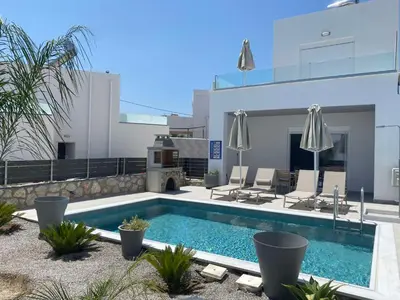 a pool with chairs and umbrellas on a building at Gennadi GEMS Villas in Gennadi
