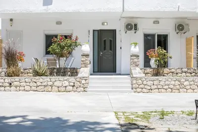a white house with a black door and a stone wall at PaMar in Faliraki