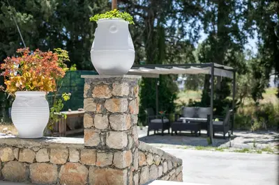 a white vase on a stone wall with flowers at PaMar in Faliraki
