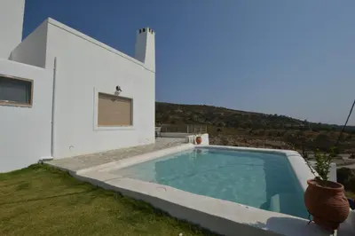 a white house with a swimming pool in the yard at Bianca Suite & Home in Psinthos