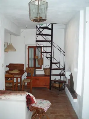 a living room with a spiral staircase and a dining room at MAÏA's House in Symi