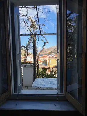 an open glass door with a view of a yard at MAÏA's House in Symi