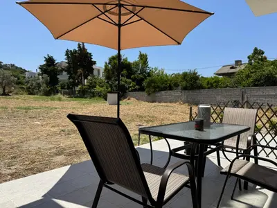 a table and chairs with an umbrella on a patio at Date Palm Studio in Kremasti