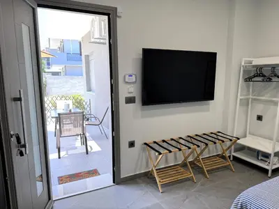 a room with a tv on a wall with a chair at Date Palm Studio in Kremasti