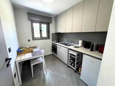 a kitchen with white cabinets and a table in it at Date Palm Studio in Kremasti