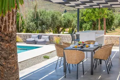 a table and chairs under an umbrella next to a pool at Villa Zen Koan in Kolimbia