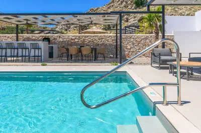 a swimming pool in a resort with a table and chairs at Villa Zen Koan in Kolimbia