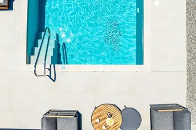 a pool with three trash cans in front of a wall at Villa Zen Koan in Kolimbia