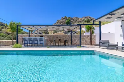 a swimming pool with a patio with a table and chairs at Villa Zen Koan in Kolimbia