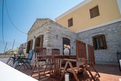 a patio with chairs and a table and a building at Mythos House - Seaside Retreat in Pedi in Symi