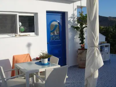 a room with a blue door and a table and chairs at Bouganville Studios Stegna in Archangelos