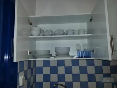 a kitchen shelf with dishes and glasses on it at Bouganville Studios Stegna in Archangelos