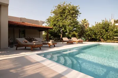 a swimming pool with chaise lounges next to a house at Casa Alini in Ialyssos