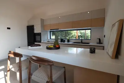 a kitchen with a white counter and two bar stools at Casa Alini in Ialyssos
