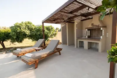 a patio with two lounge chairs under a pergola at Casa Alini in Ialyssos