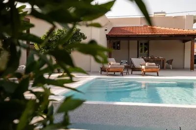 a swimming pool next to a house with a patio at Casa Alini in Ialyssos
