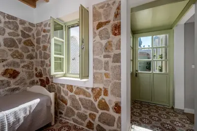 a bedroom with a green door and a stone wall at Siliguri Traditional House in Rhodes Town