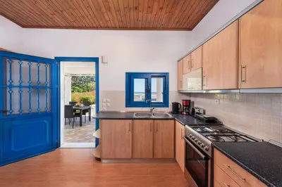 a kitchen with wooden cabinets and a blue door at PARADISE SEA HOUSE a in Haraki
