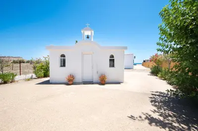 a small white chapel with a white door on a dirt road at PARADISE SEA HOUSE a in Haraki