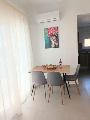 a dining room table with two chairs and a painting at Platanou 21 Apartments in Kremasti