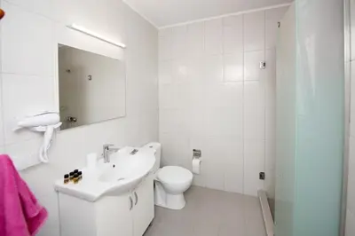 a white bathroom with a toilet and a sink at Platanou 21 Apartments in Kremasti