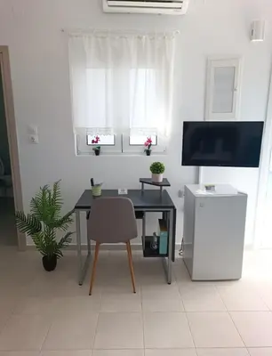 a room with a table and a chair and a television at Platanou 21 Apartments in Kremasti