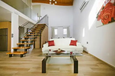 a living room with a white couch and stairs at Semi-detached house with private pool in Lardos