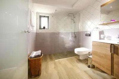 a white bathroom with a toilet and a sink at Semi-detached house with private pool in Lardos