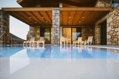 a villa with a swimming pool with chairs and a building at Semi-detached house with private pool in Lardos