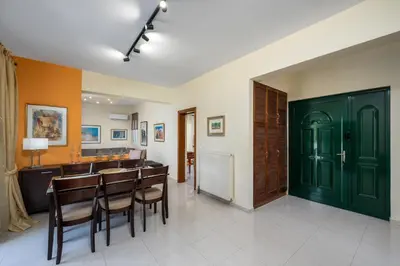 a dining room with green doors and a table and chairs at Euphoria Villa up to 5 in Ialyssos