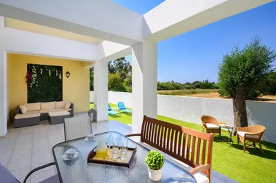 a patio with a table and chairs and a couch at Euphoria Villa up to 5 in Ialyssos