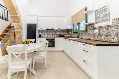 a kitchen with white cabinets and a white table and chairs at Filoxenia House in Archangelos
