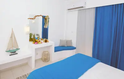 a bedroom with blue curtains and a bed and a desk at Mojito Beach Rooms in Lachania