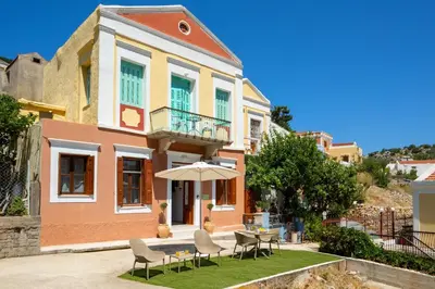 a house with a table and chairs and an umbrella at Pissadi House in Symi