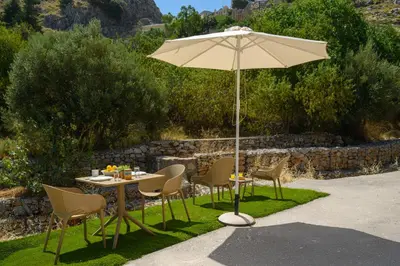 a table and chairs with an umbrella in the grass at Pissadi House in Symi