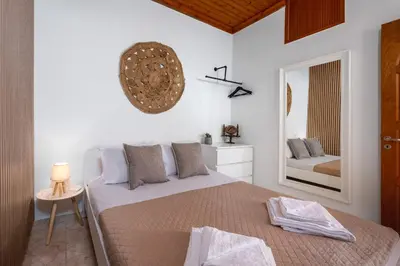 a white bedroom with a bed and a mirror at Pissadi House in Symi