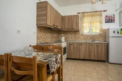 a kitchen with wooden cabinets and a table and a refrigerator at Dimitris studios & apartments in Faliraki
