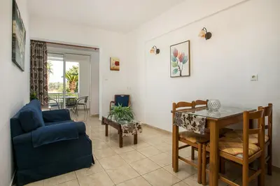 a living room with a table and a blue chair at Dimitris studios & apartments in Faliraki