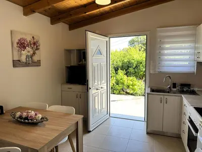 a kitchen with a table and a door to a yard at The Wooden Nest in Asgourou