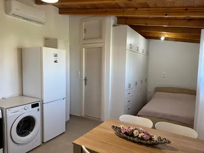 a kitchen with a refrigerator and a table with a washer at The Wooden Nest in Asgourou