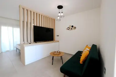 a living room with a couch and a flat screen tv at Olympian Apartments in Ialyssos