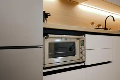 a silver microwave in a kitchen with white cabinets at Olympian Apartments in Ialyssos